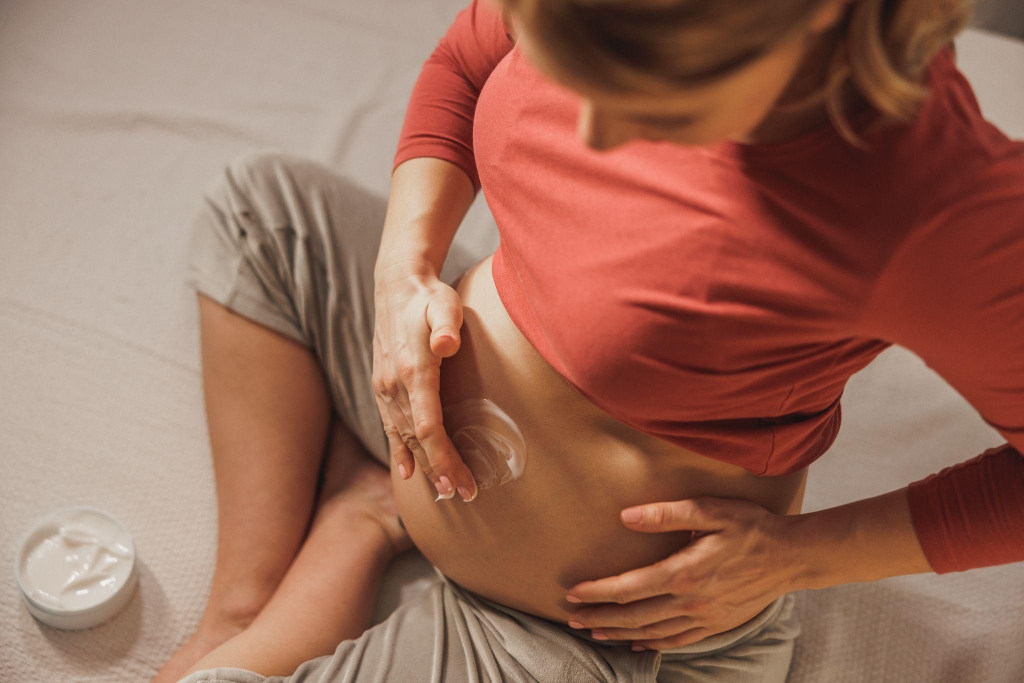 A close-up of a woman applying scar cream to her C-section incision.