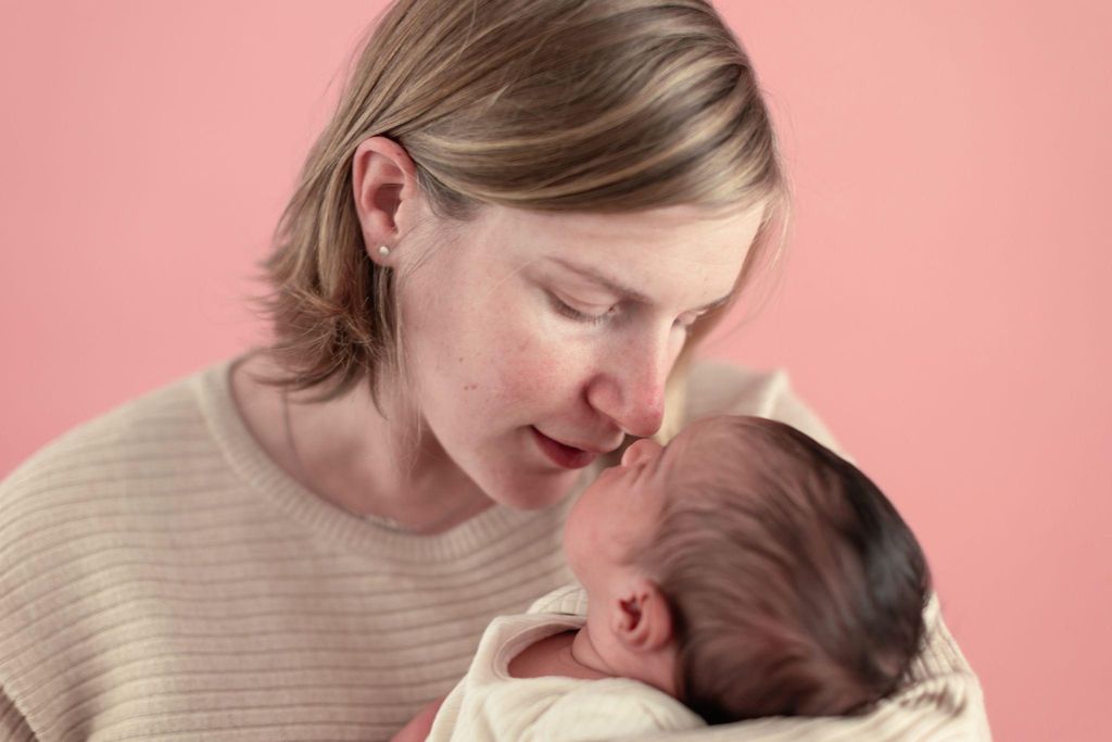 New mother cradling her baby, symbolizing postpartum recovery.