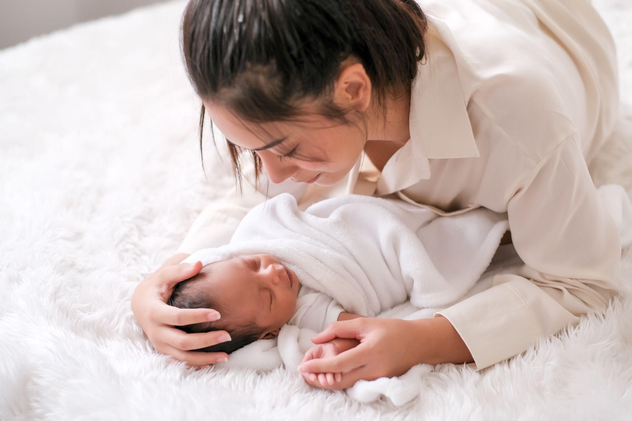 A tired parent cradling a newborn baby in a dimly lit room during the night, highlighting the challenges of the second night syndrome.