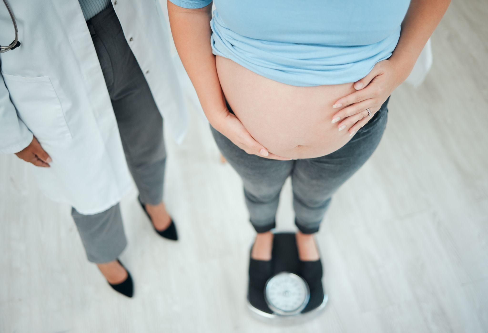 A pregnant woman getting weighed by a doctor during her antenatal journey.