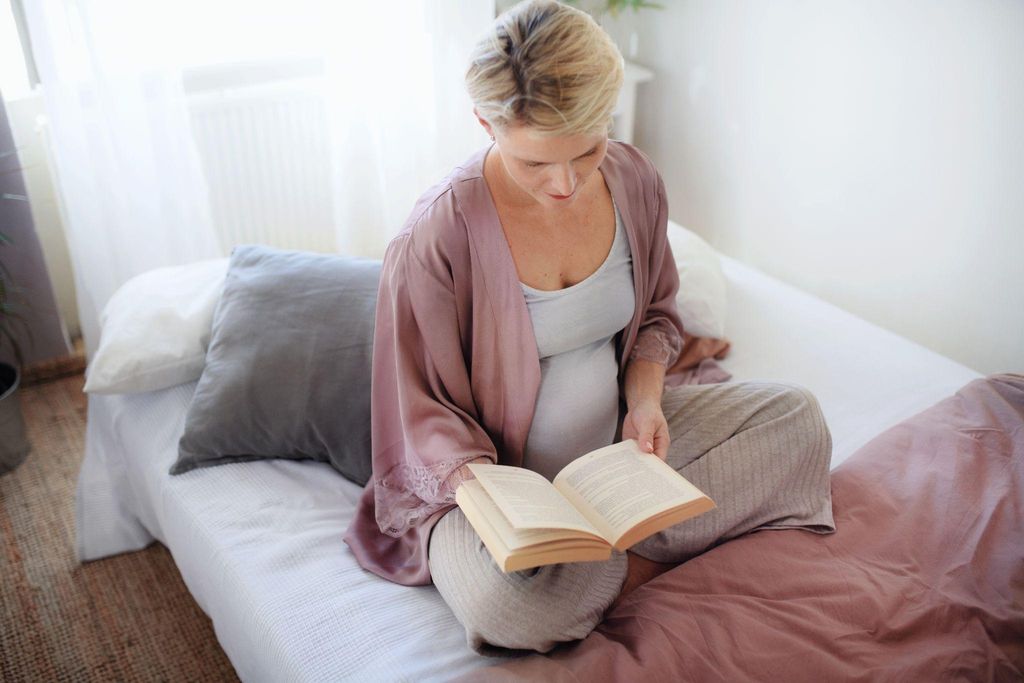 "Pregnant woman reading a biography in a peaceful living room."