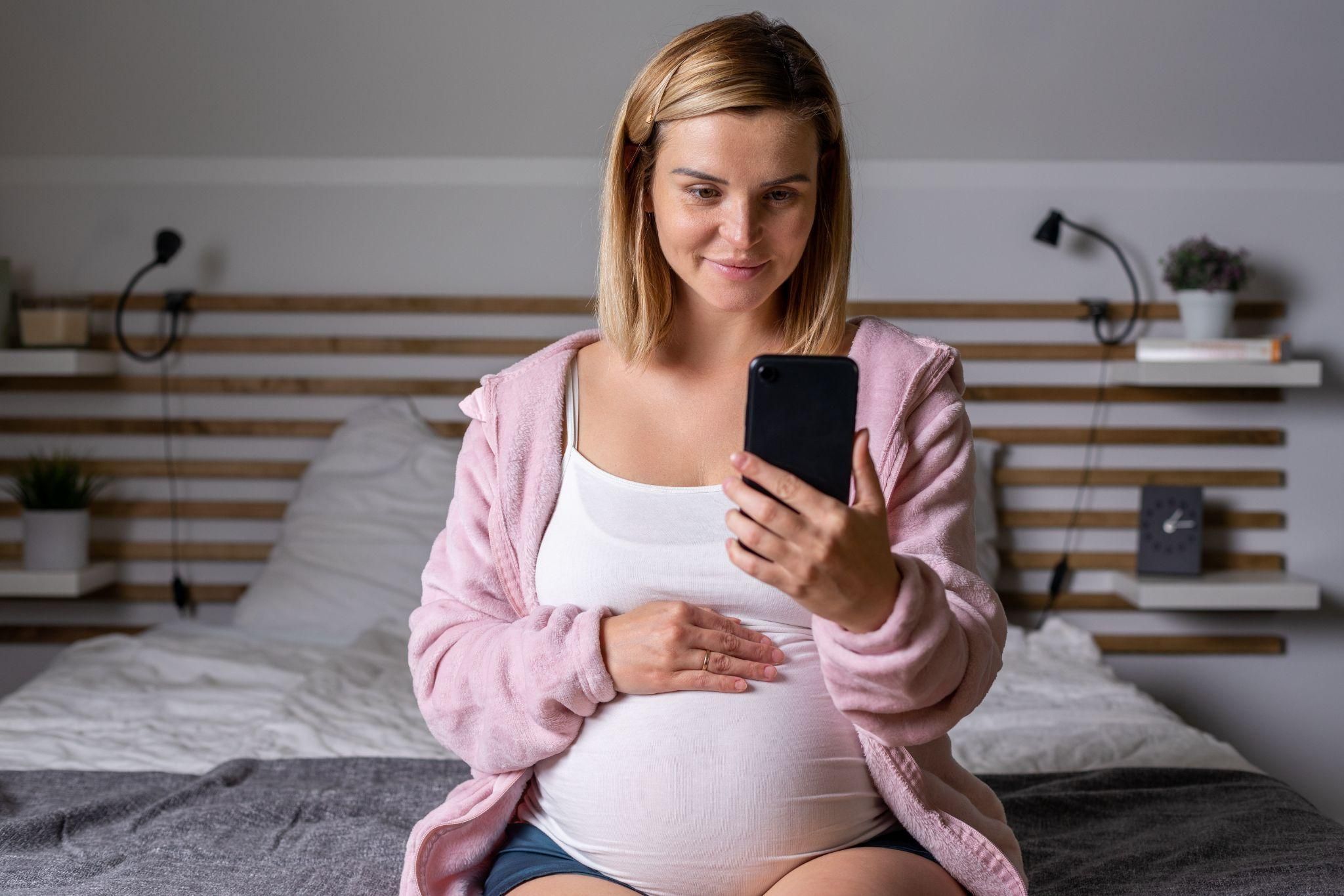 A single pregnant mum relaxing on a couch, looking content.