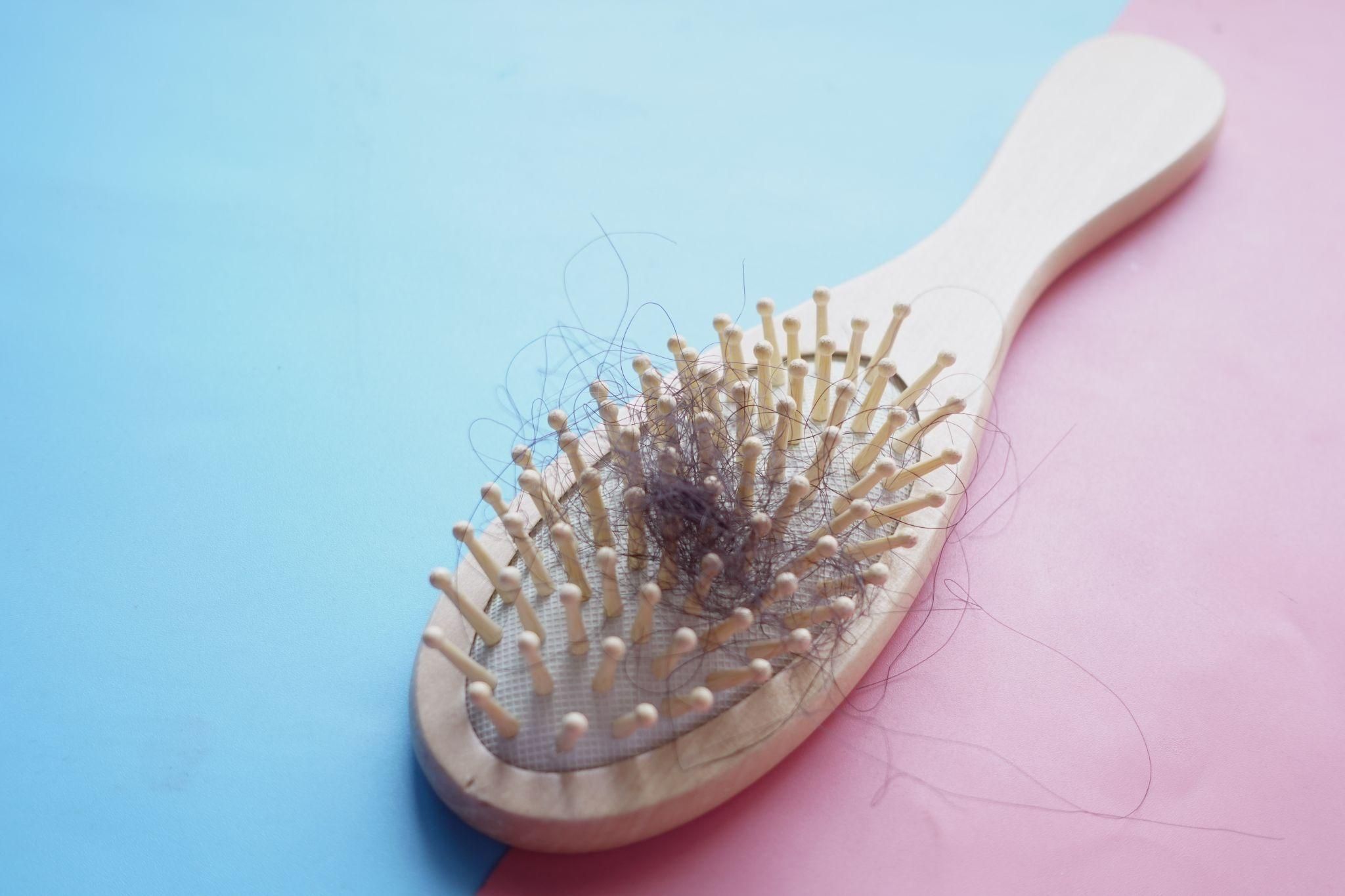 A mother gently combing her healthy postpartum hair while smiling.