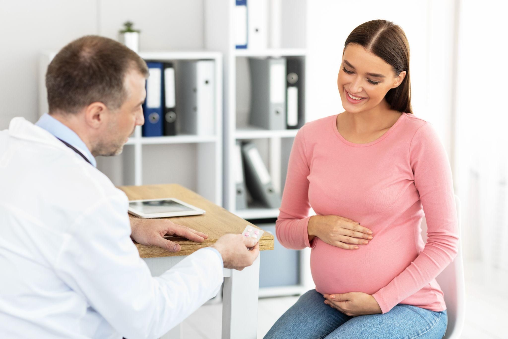 Pregnant woman smiling during an antenatal NHS appointment.