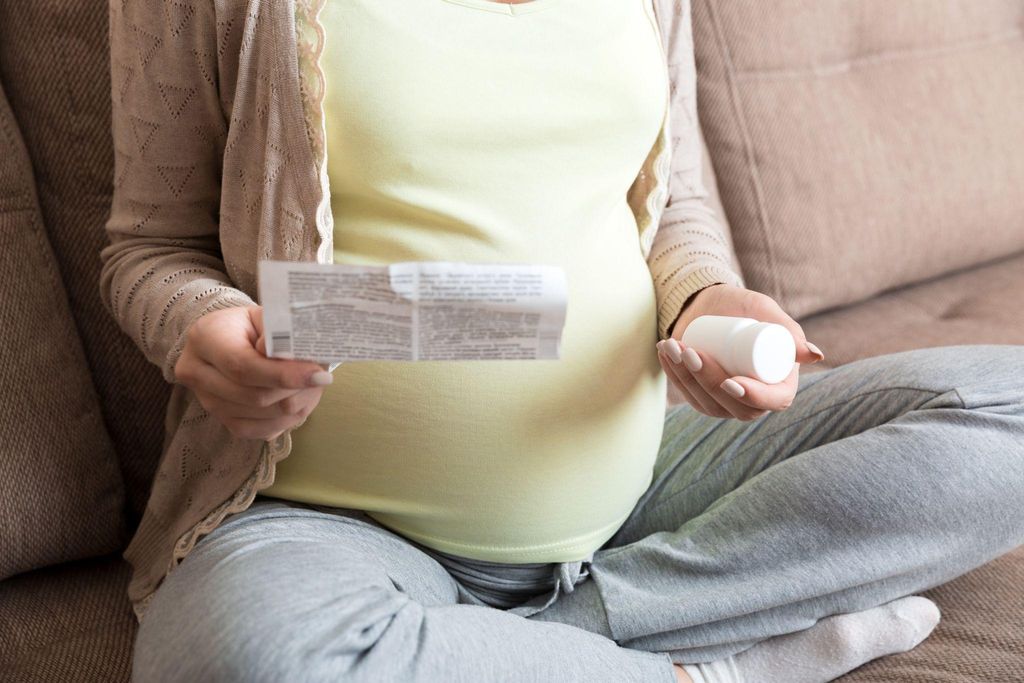 A pregnant woman taking anti-sickness medication to manage nausea during pregnancy.