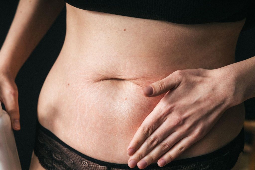 A woman gently massaging her C-section scar with natural oils.