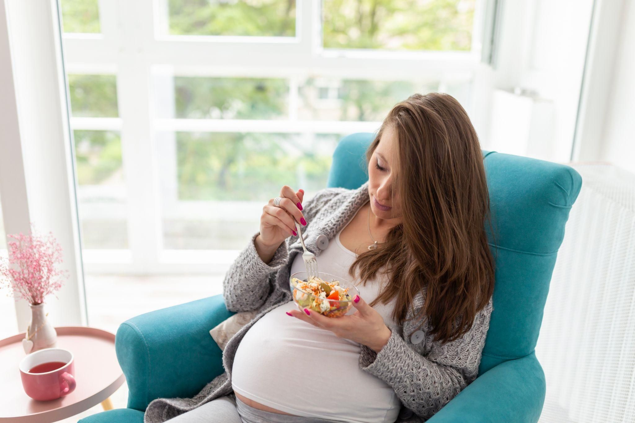 Pregnant woman enjoys salad for lunch as part of her antenatal diet.