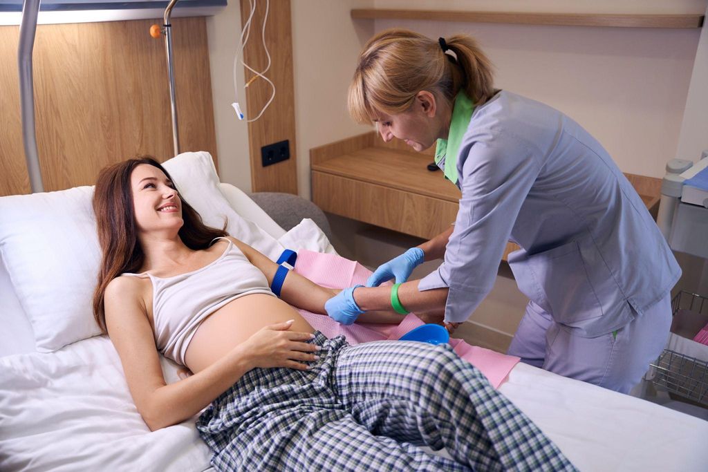 Nurse takes blood sample for testing from pregnant woman during routine antenatal care appointment.