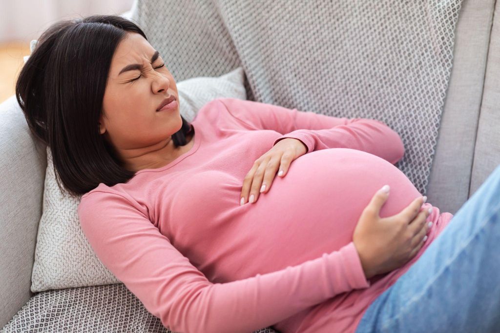 Pregnant woman in pain on couch.