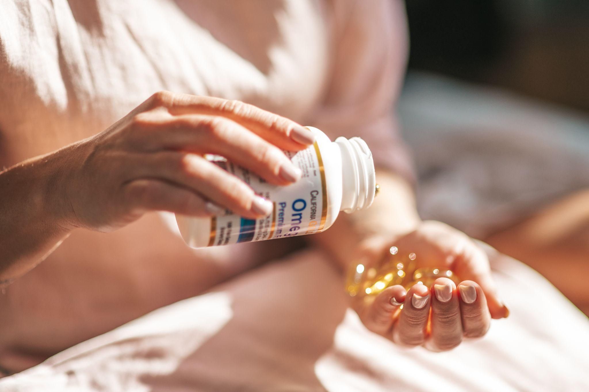 Pregnant woman looks at way too many Omega 3 fish oil capsules for a single dose.