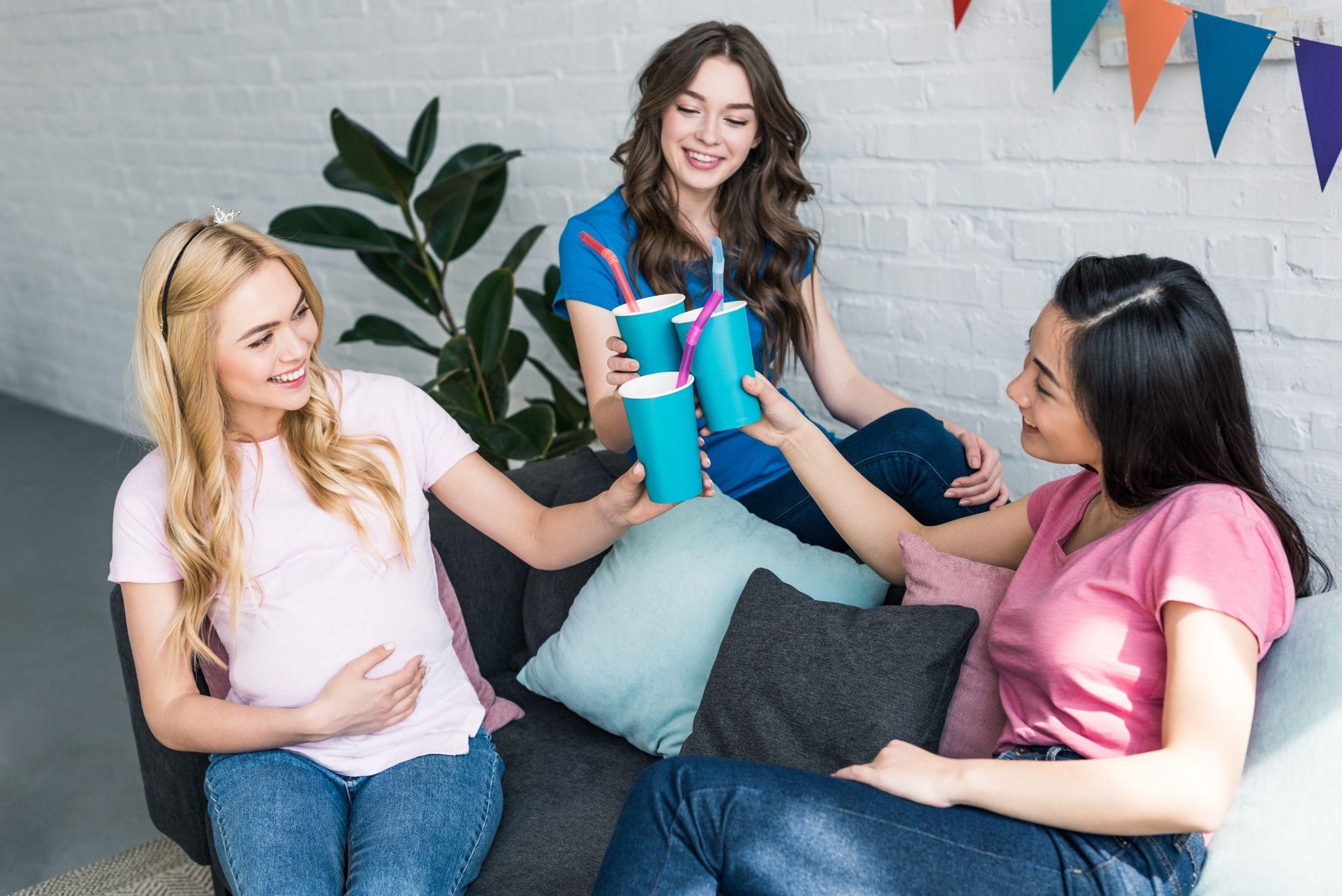 Pregnant woman with her friends, explaining her financial situation over a cup of tea.