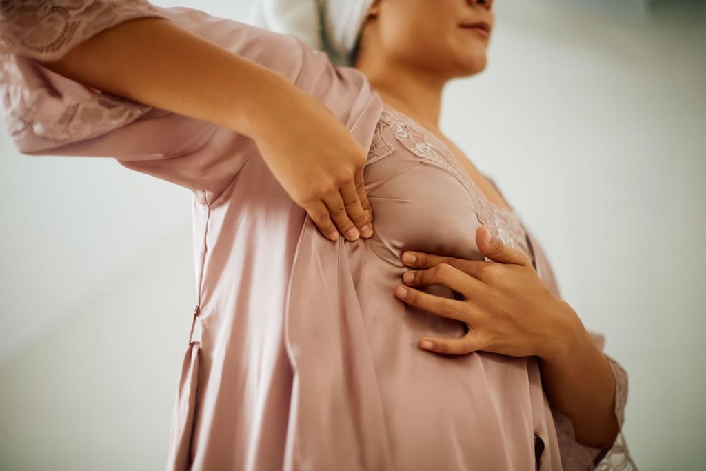 Pregnant woman checking her breasts for changes during pregnancy as part of regular self-care.